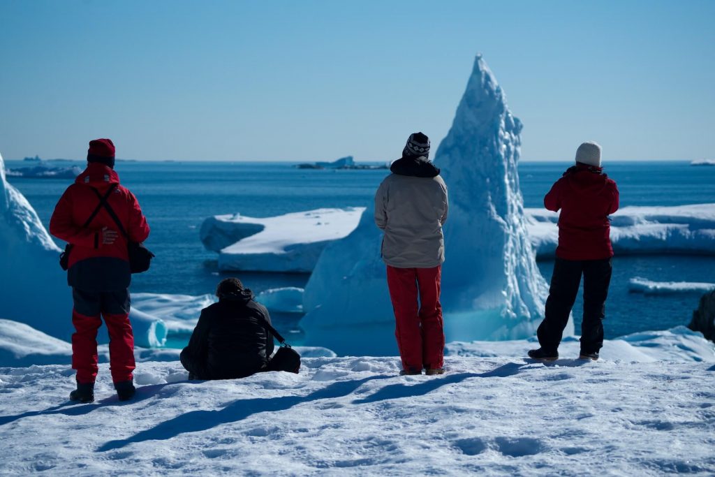 Quatre personnes équipées de matériel arctique, explorant le terrain glacé.